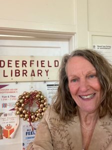 Phot of Susan smiling in front of a sign that says "Deerfield Library"